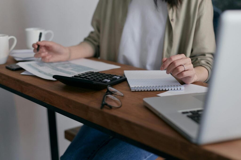 a woman at a desk with notepad, calculator, and laptop