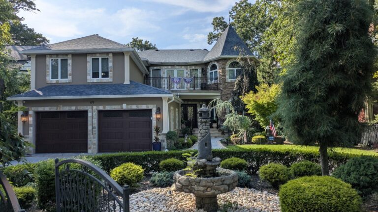 Large modern house with a stone fountain and clipped hedges in the front garden
