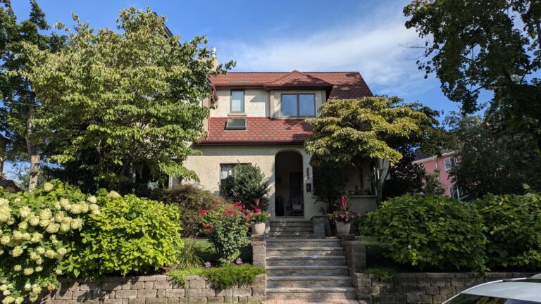 Stucco house with a red tiled roof and hydrangeas along the front steps