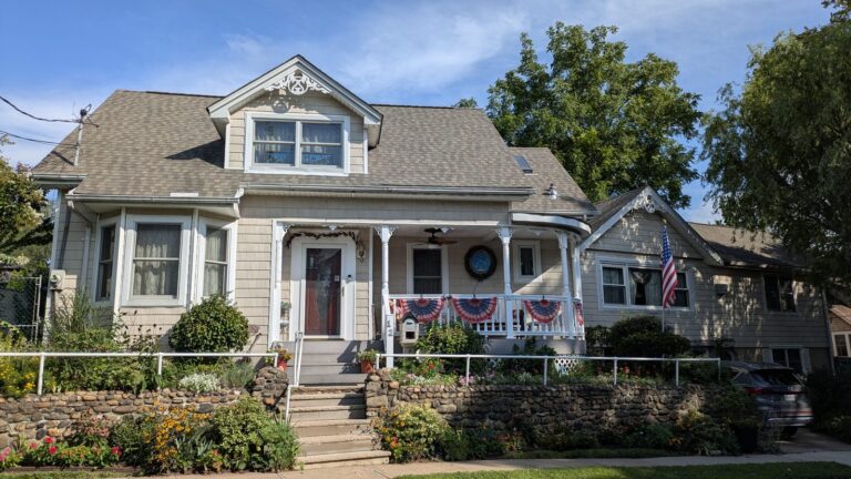 Grey Victorian house with a covered porch and bunting along the rail