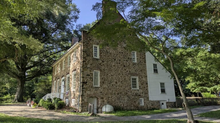 Stone side elevation of the Conference House under old trees