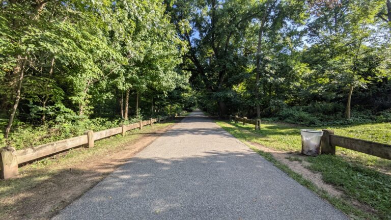 Gravel path through Conference House Park beside a timber rail fence